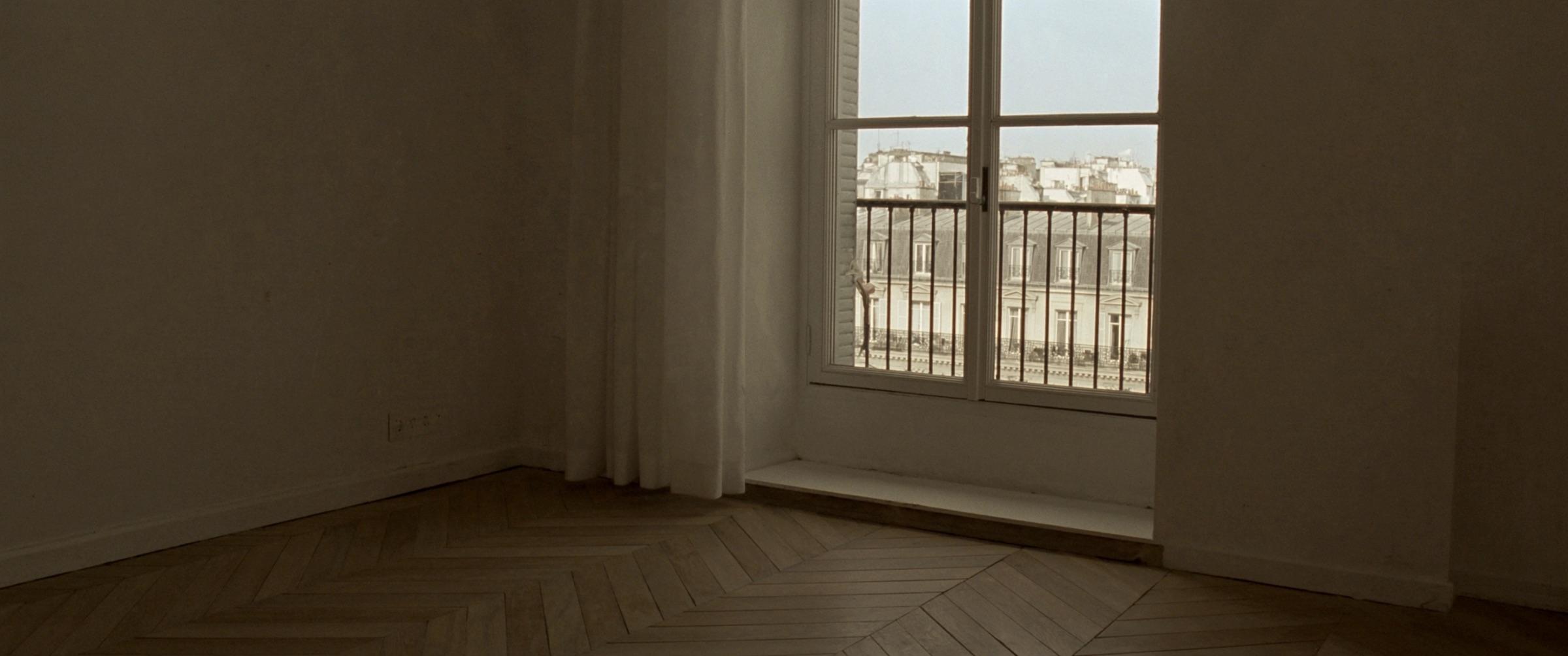 An empty finished flat: herringbone parquet, white walls, tall windows opening on the city.